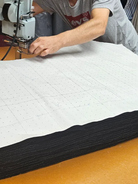 Pantalon en tissu bleu ciel imprimé de motifs ornementaux bordeaux, posé à plat.