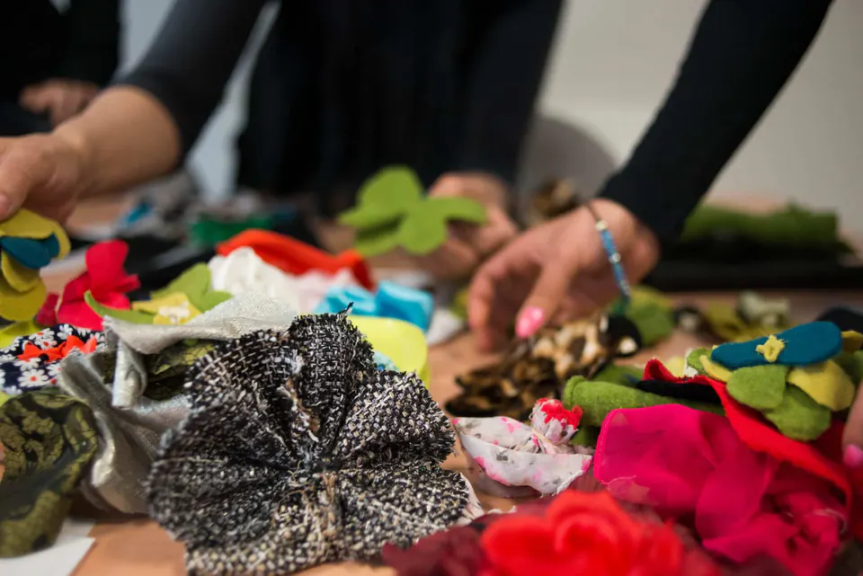Handen sorteren bloemen van stof en vilt in alle kleuren op een werktafel.