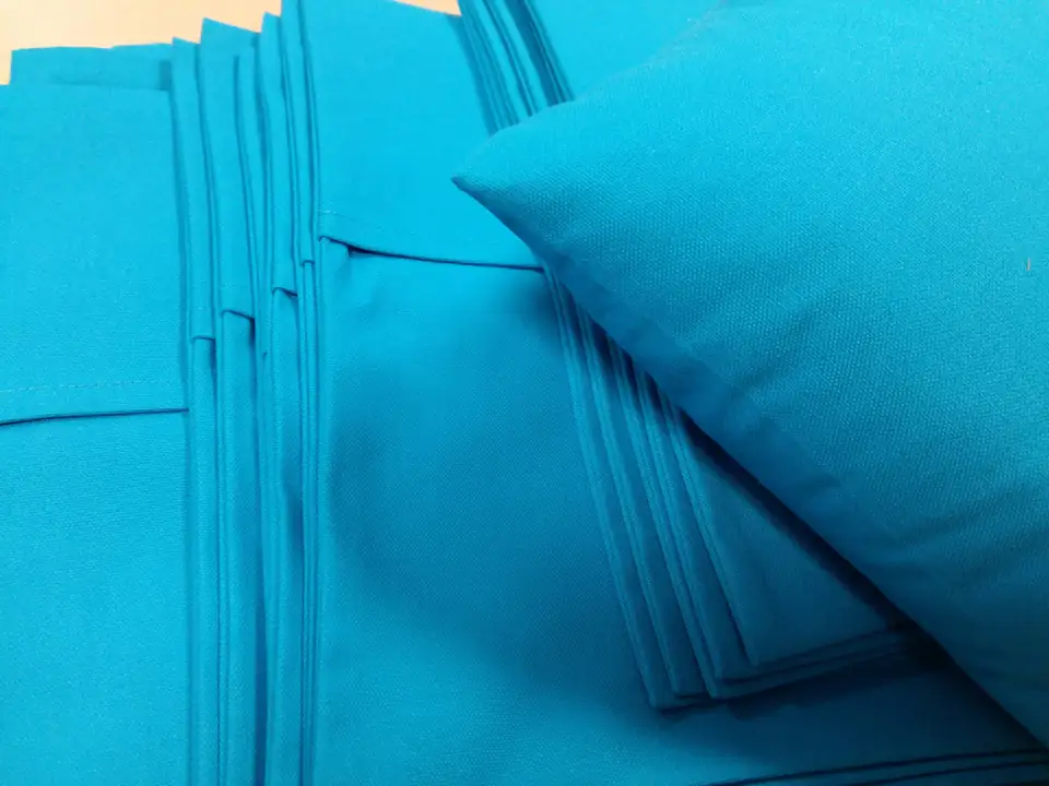 Stapel opgevouwen turquoise hoezen en een bijpassend kussen.