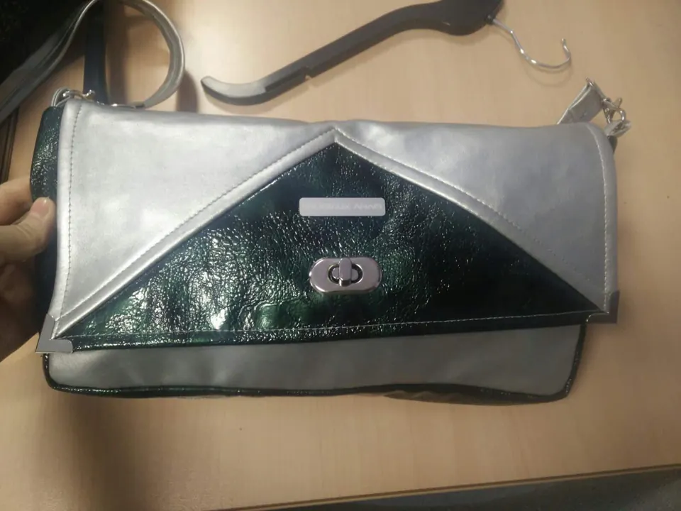 Prototype de pochette argentée à rabat, avec un empiècement vernis vert foncé et un fermoir tournant.